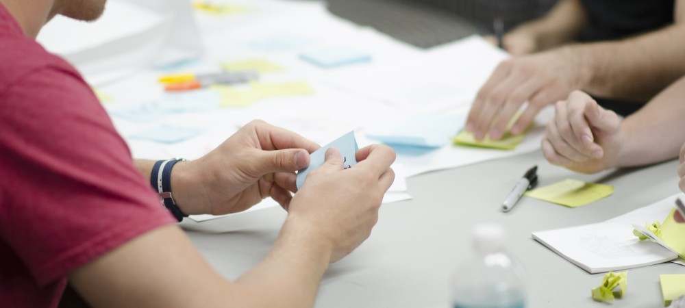 Desk workspace with man working with sticky notes.