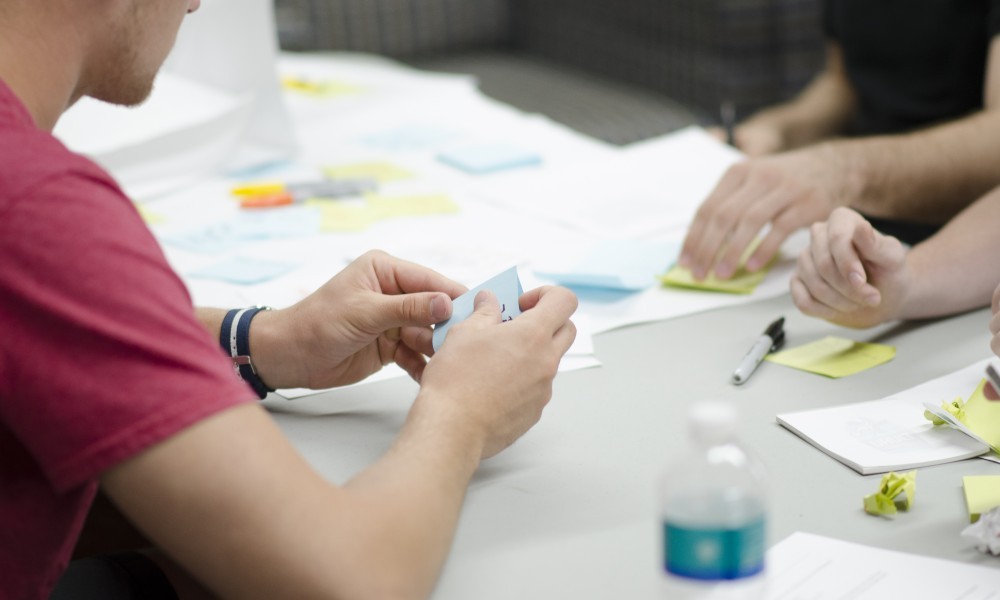 Desk workspace with man working with sticky notes.